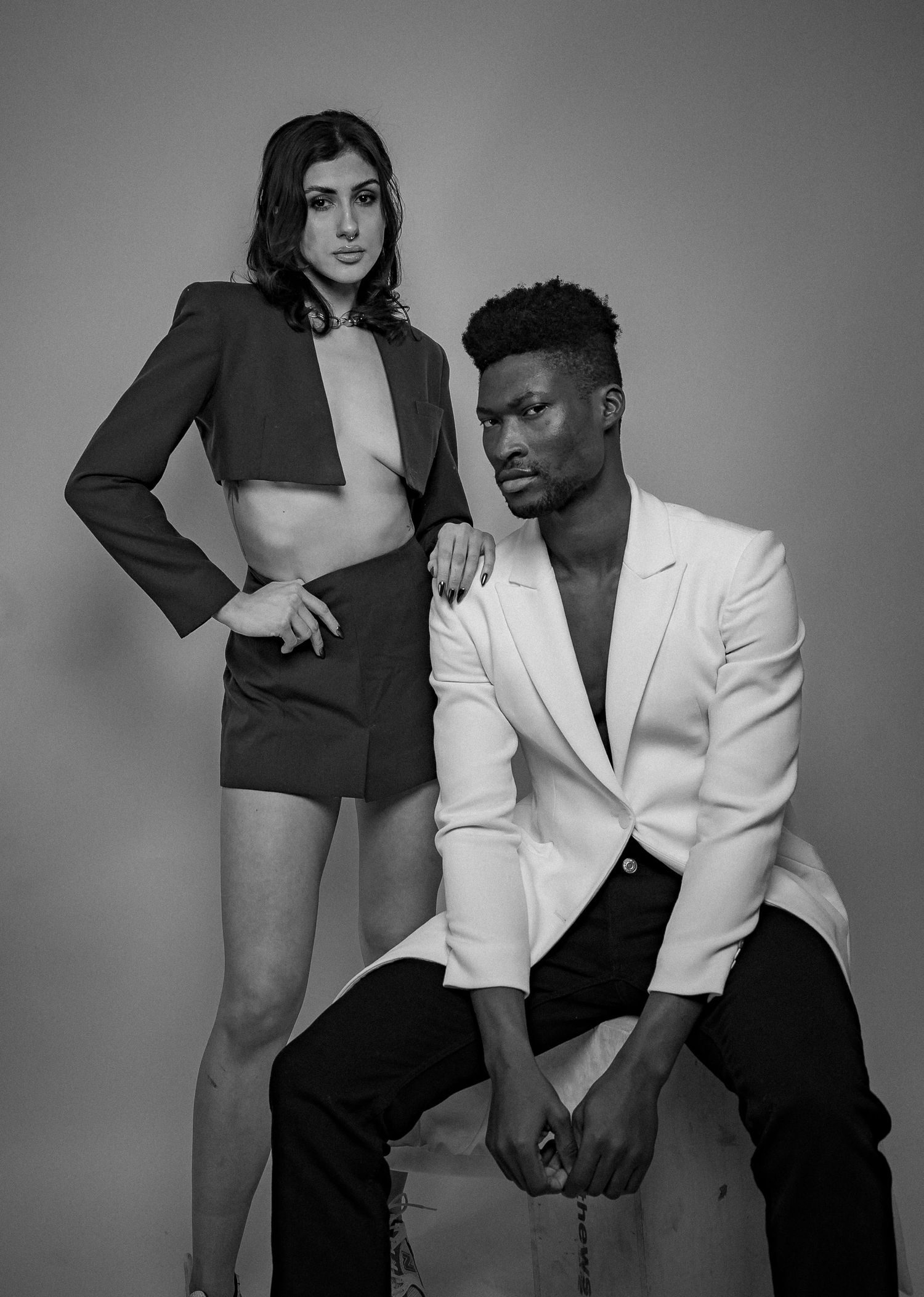 A woman in a dark blazer and a man in a white suit, photographed in black and white.